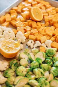 butternut squash, brussel sprouts, cauliflower and lemon on a baking sheet