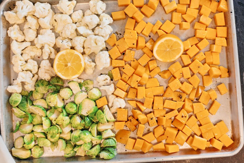 butternut squash, cauliflower, brussel sprouts and lemon on a baking sheet