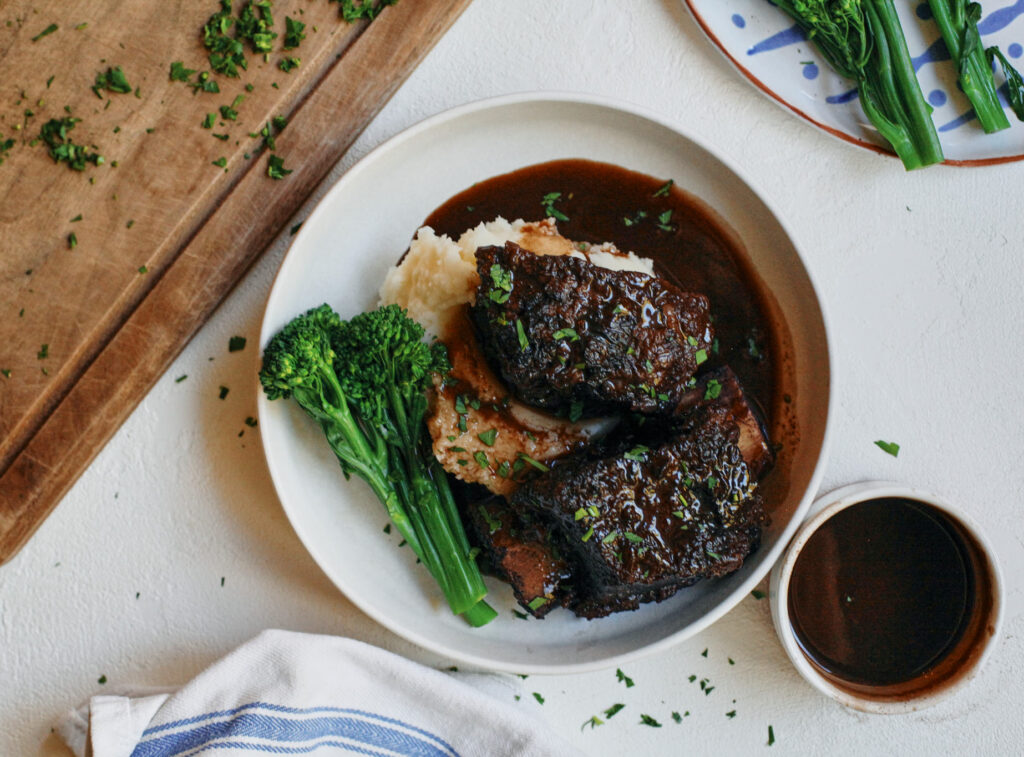 red wine braised short ribs over mashed potatoes with broccolini and red wine gravy poured over top