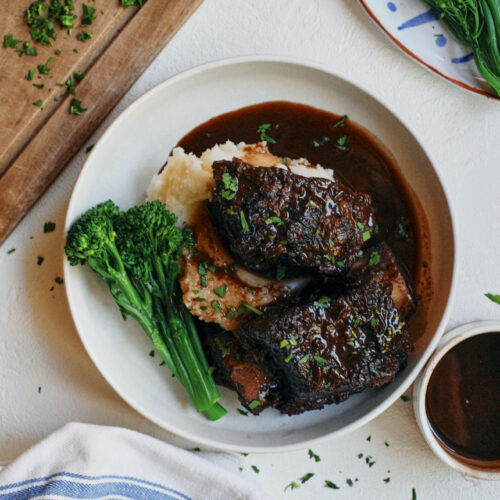 red wine braised short ribs over mashed potatoes and broccolini with a red wine sauce poured over top