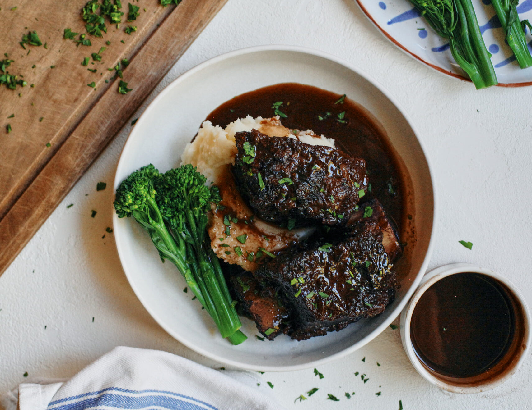 red wine braised short ribs over mashed potatoes and broccolini with a red wine sauce poured over top
