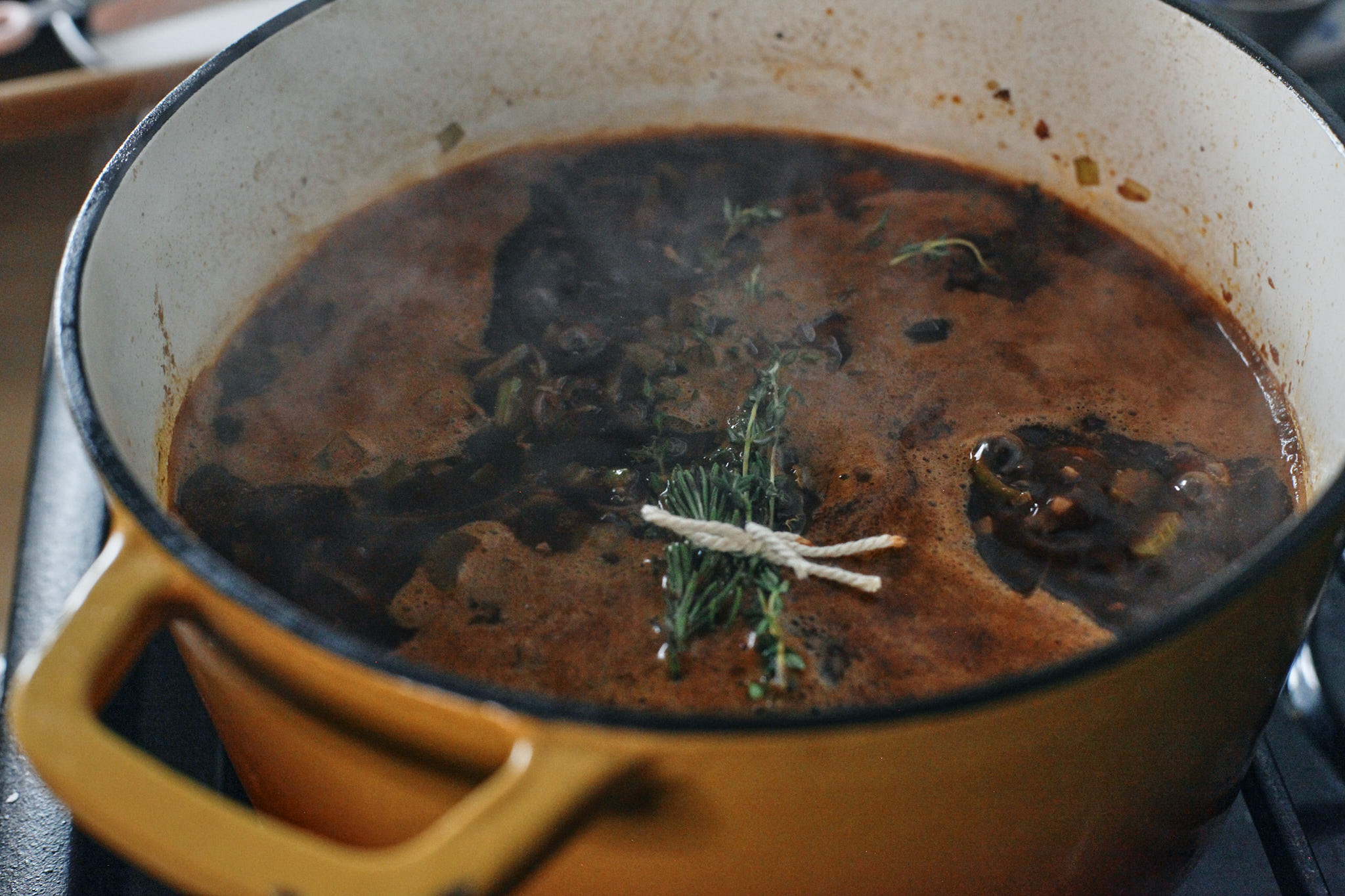oxtail ready to braise with the wine and stock up to a simmer, finished with a bouquet of herbs