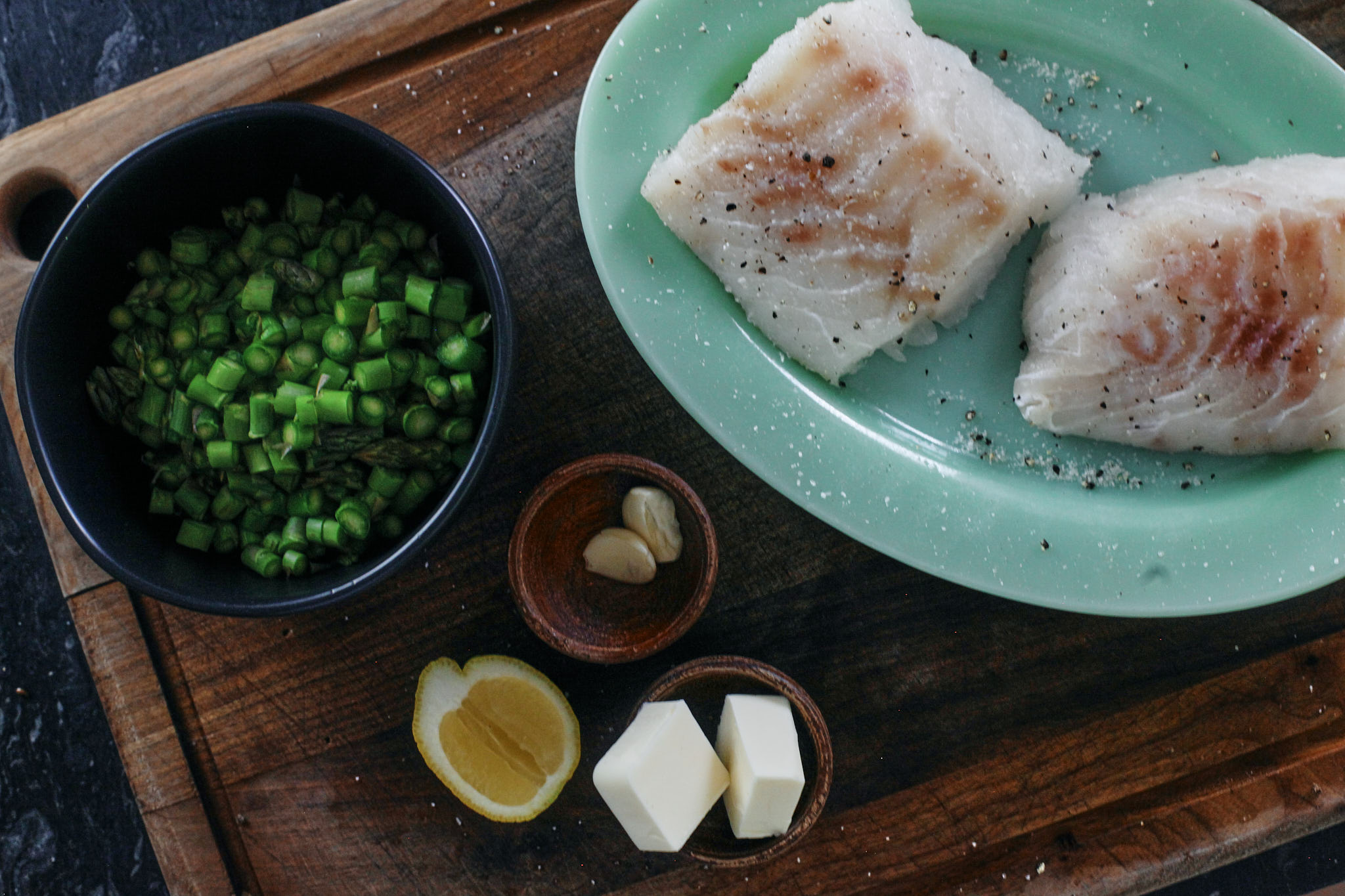 prep for lemon butter cod: chopped asparagus, cod filets, lemon, garlic and butter.