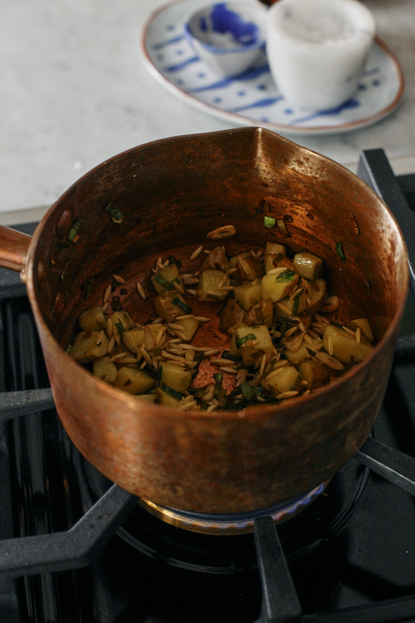 chopped leek, potato and garlic in a pot sautéeing