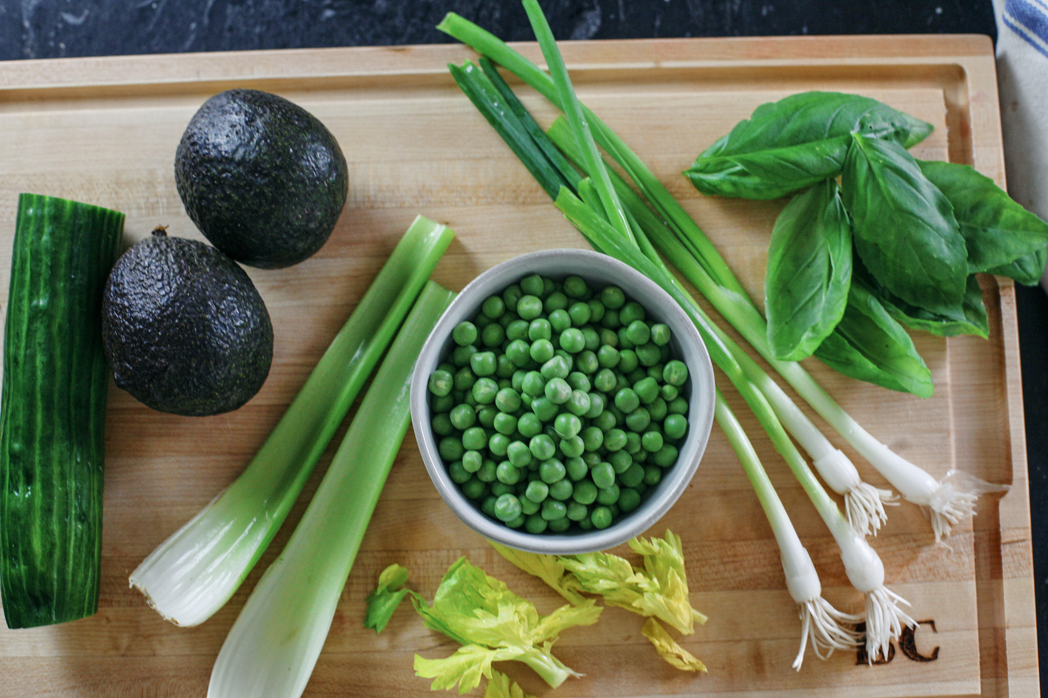 prep for the green goddess salad: cucumber, avocado, celery, peas, basil, green onions