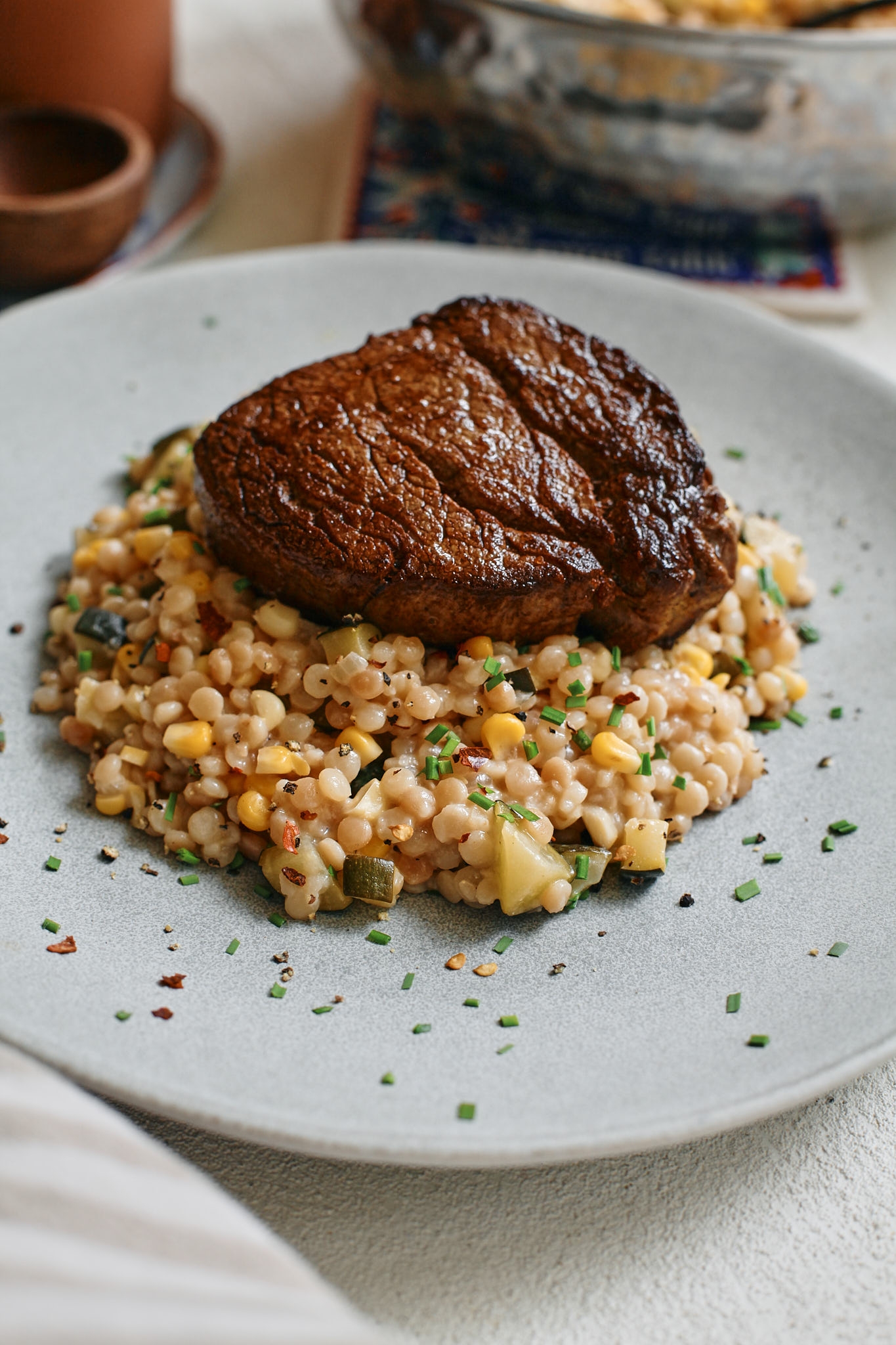 boursin creamy corn pearl couscous with steak on top