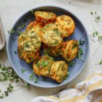 mini spring frittata bites in a blue serving bowl, topped with micro greens