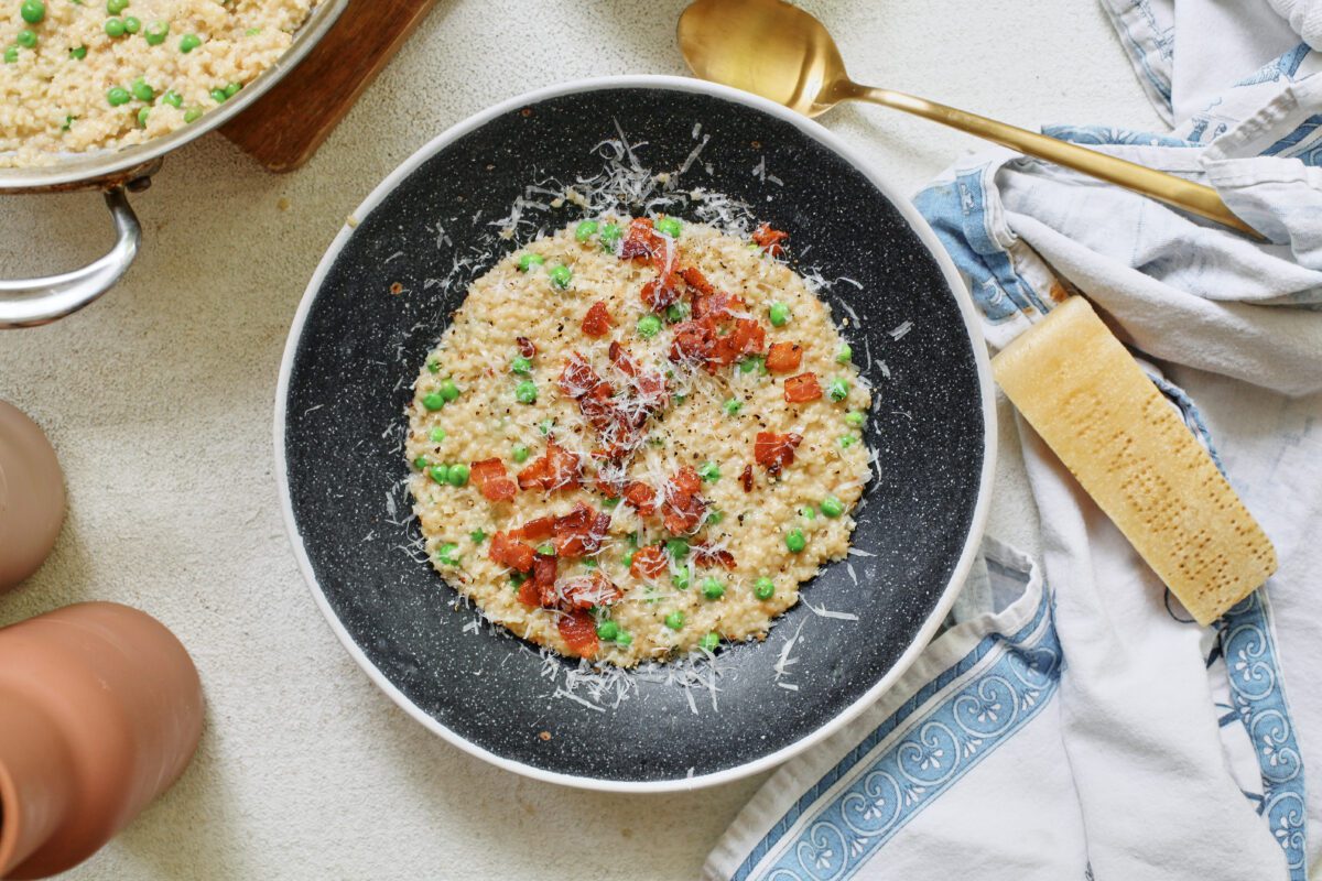 cheesy bacon pastina with peas, served in a black bowl