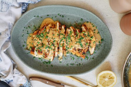 sliced chicken breast with the garlic shallot cream sauce poured on top finished with chives
