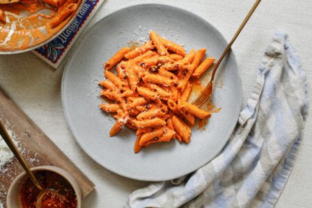 chili oil penne alla vodka on a plate with a gold fork