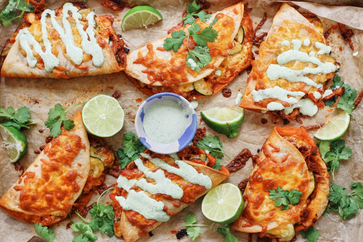 baked chorizo sheet pan tacos served on a pan with limes, cilantro, and jalapeño garlic crema
