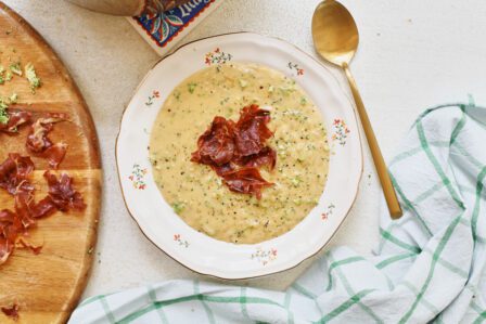 creamy broccoli cheddar orzo soup with crispy pancetta on top in a bowl