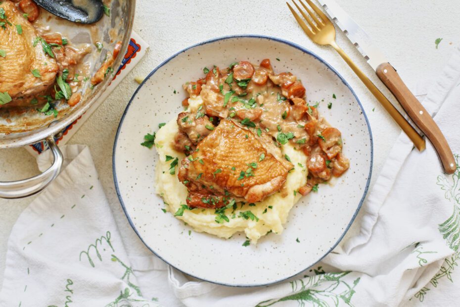 plated coq au vin blanc over a bed of creamy mashed potatoes with fresh Italian parsley on top