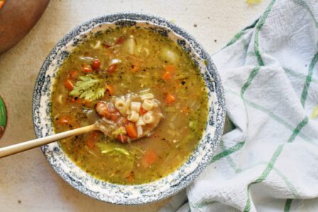 pesto minestrone soup in a white and blue floral-patterned bowl