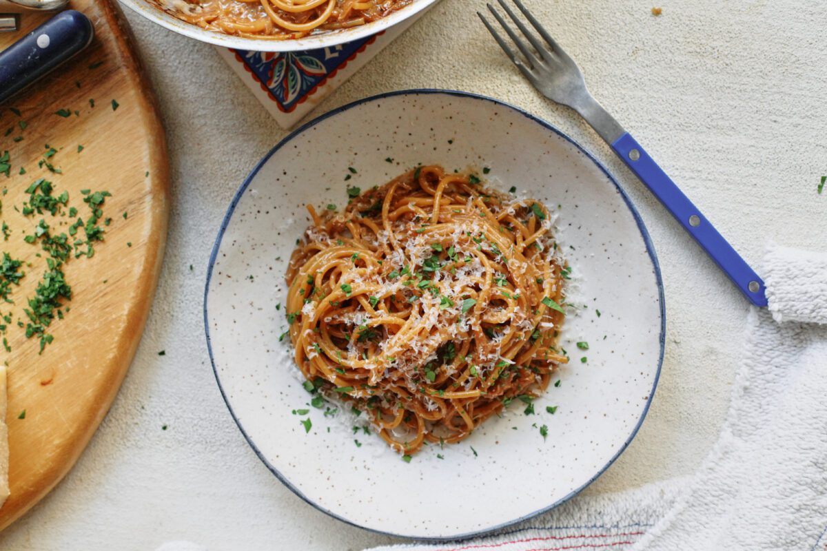French onion spaghetti in a shallow white bowl with a black rim