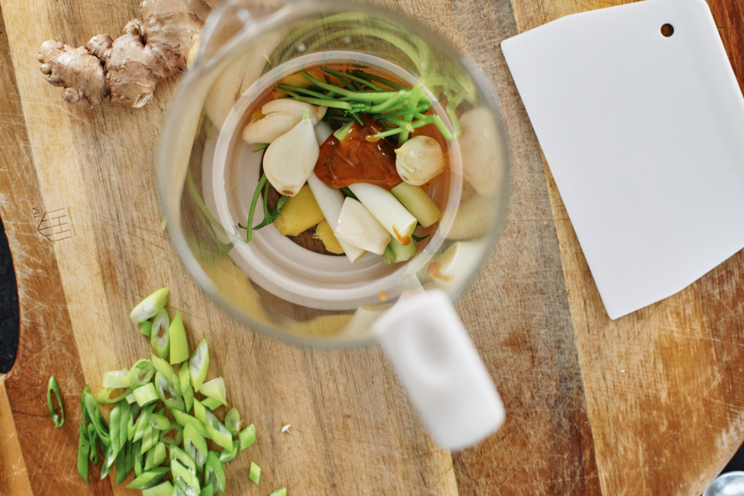 overhead photo of a glass coffee french press filled with soup aromatics