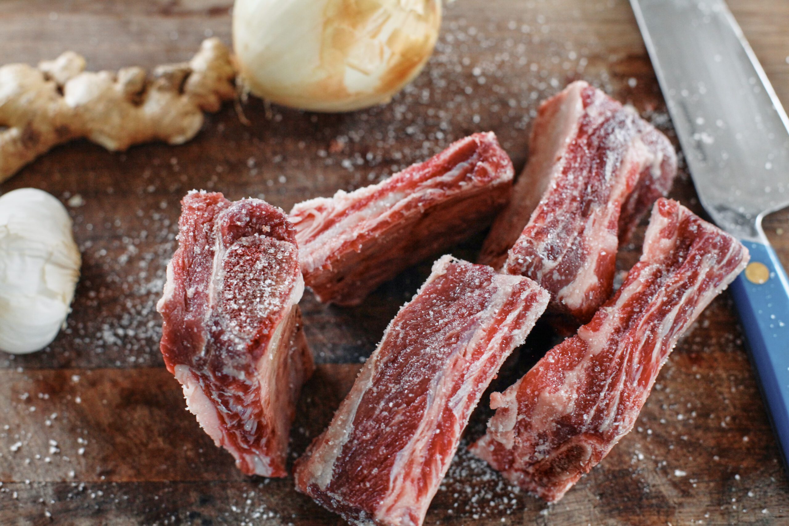 salted raw beef short ribs on a wood cutting board