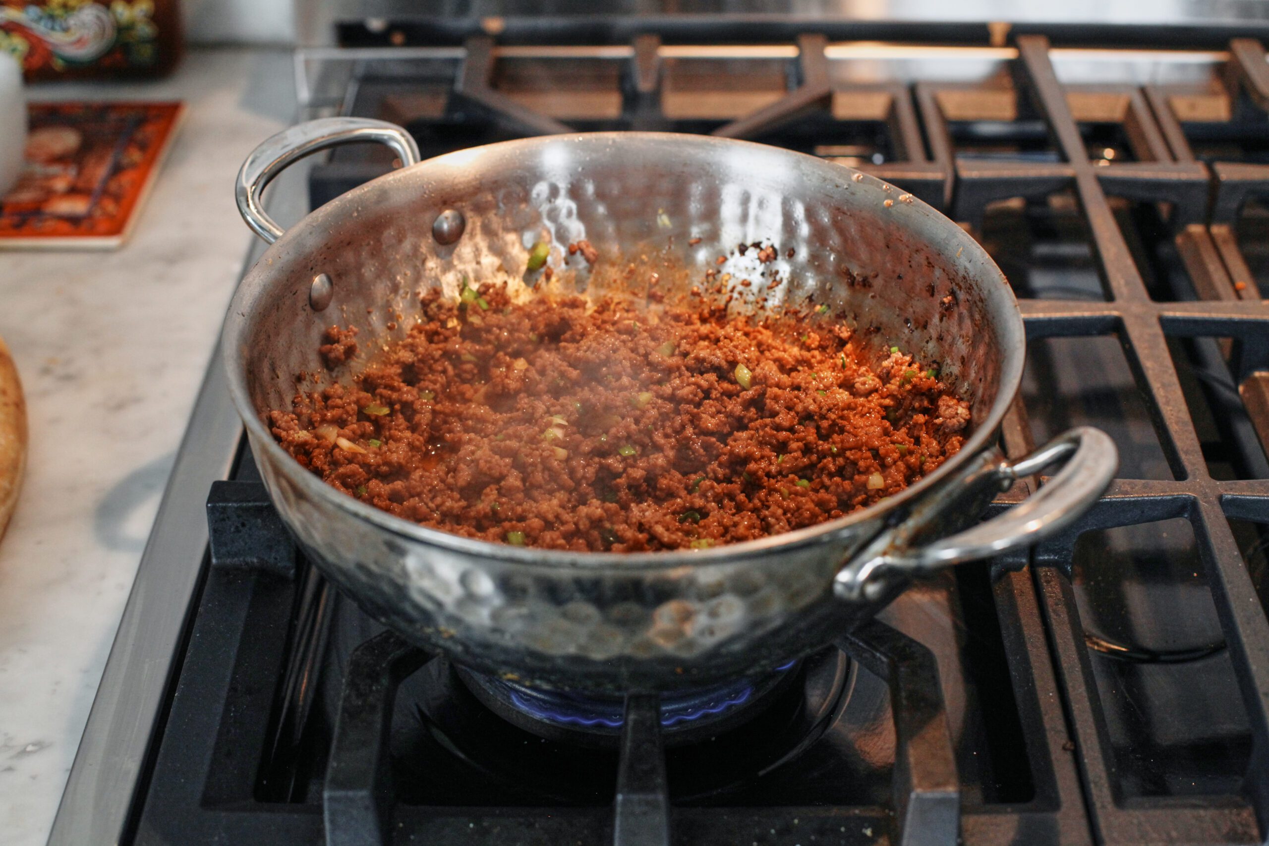 korean style ground beef cooking in a hammered steel skillet on the stove