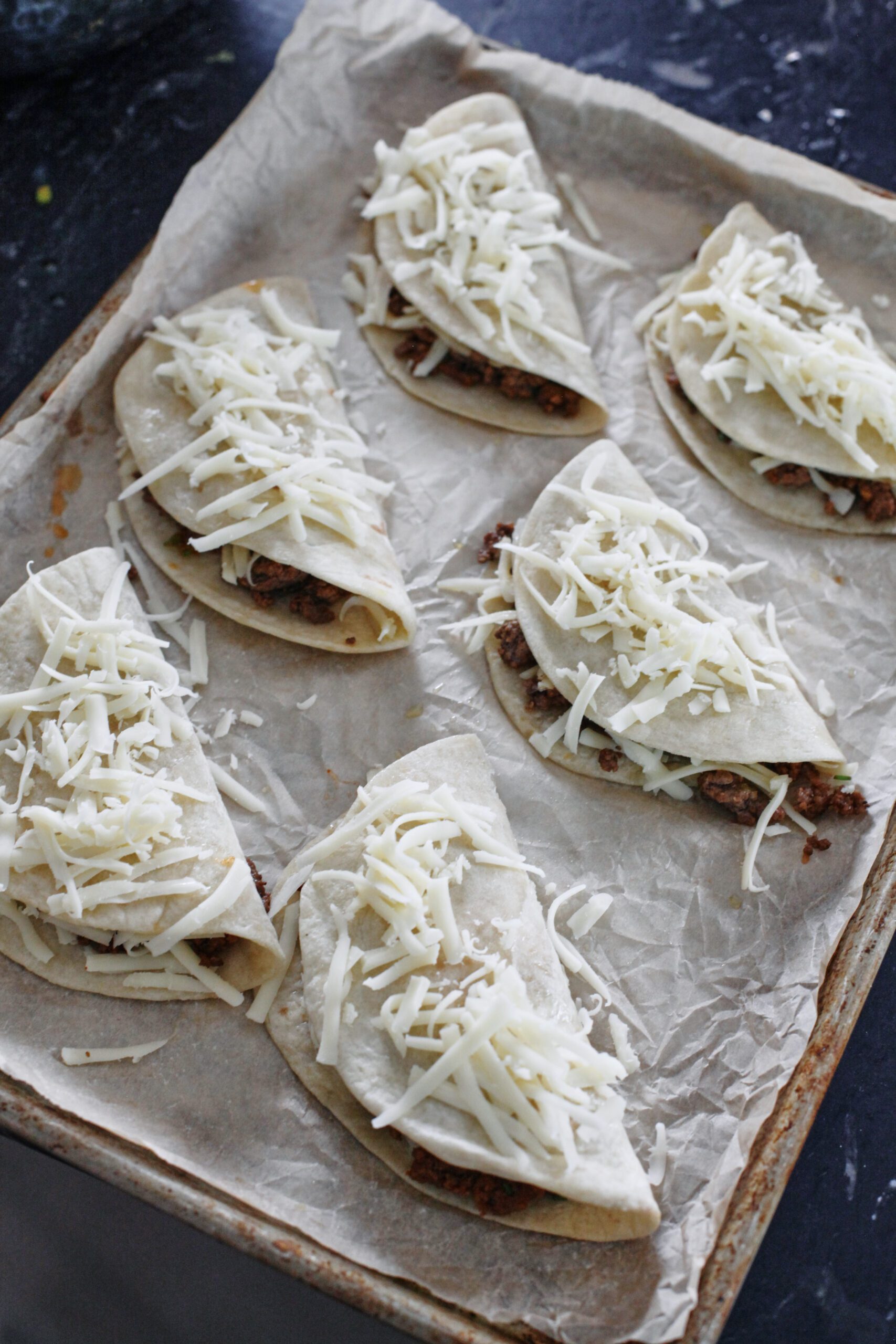 six tacos with cheese on top before being baked