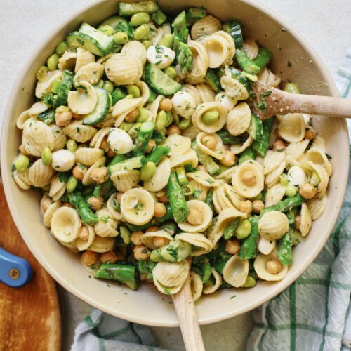 lemon herb spring pasta salad in a large serving bowl with two wooden serving spoons