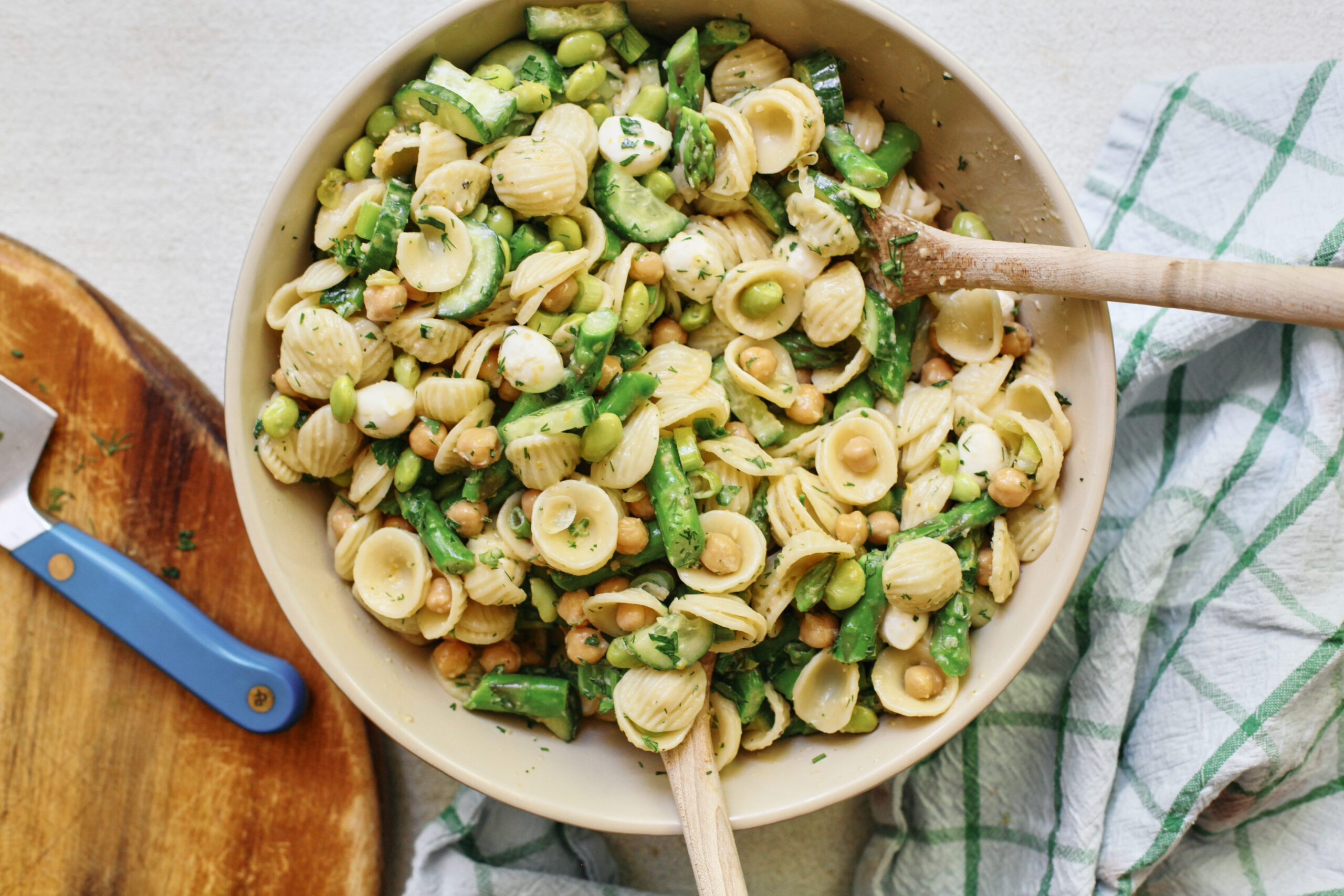 lemon herb spring pasta salad in a large serving bowl with two wooden serving spoons
