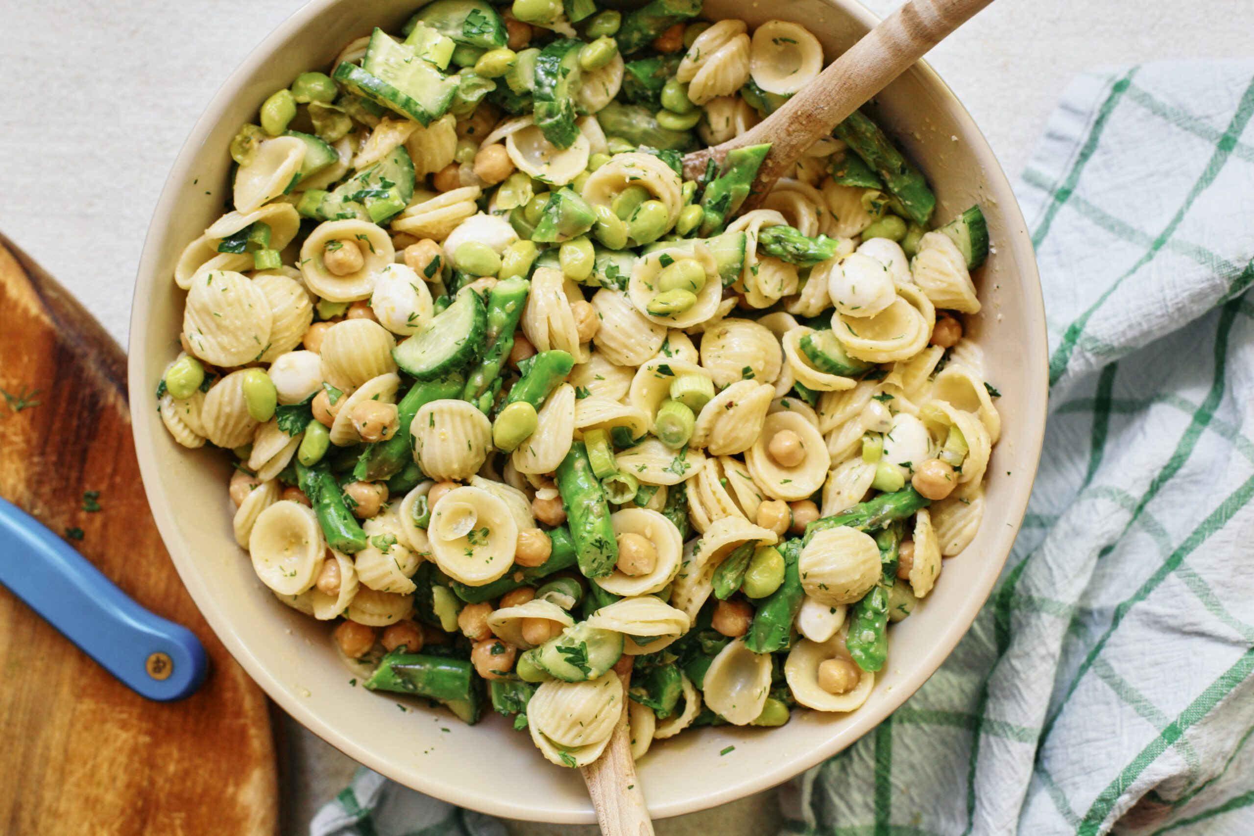 lemon herb spring pasta salad in a large serving bowl with two wooden serving spoons