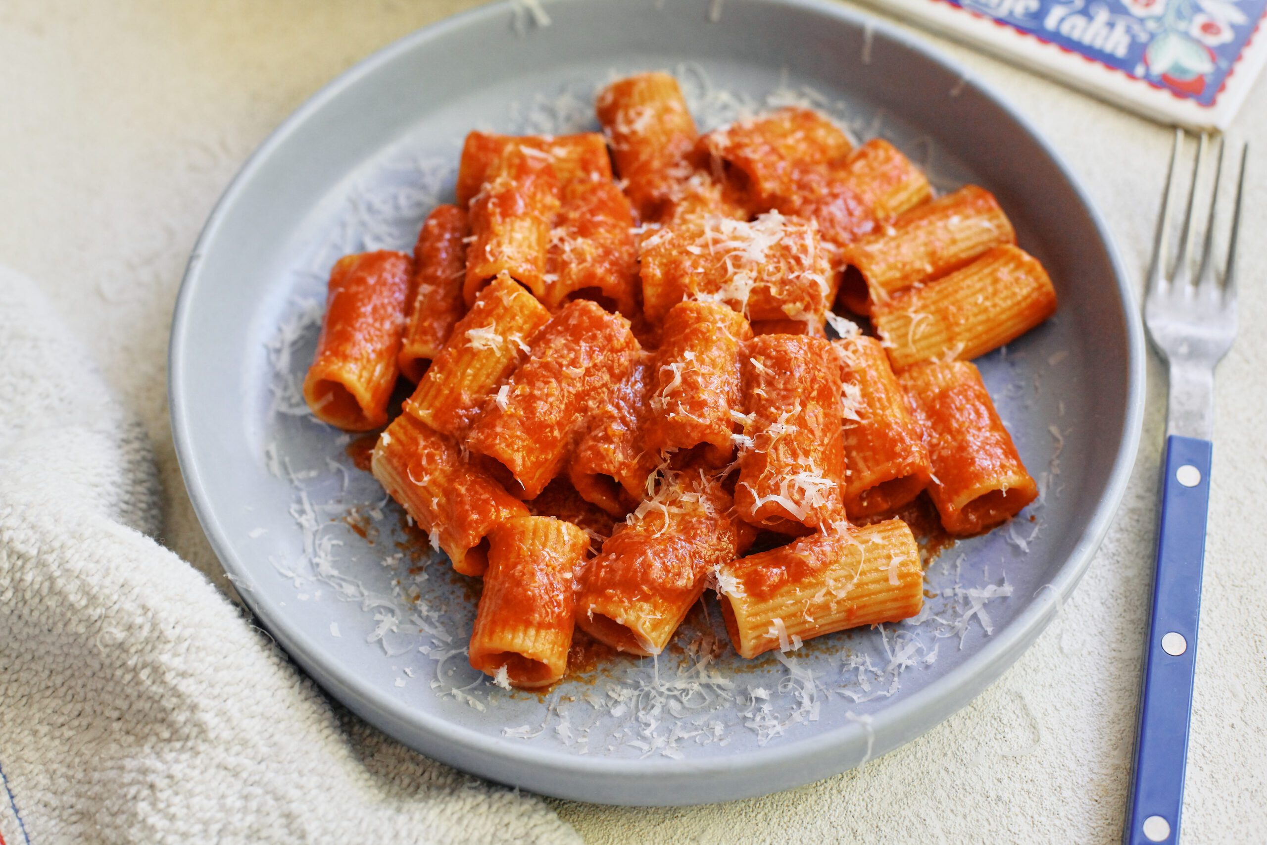 Tomato ginger butter rigatoni on a light blue plate