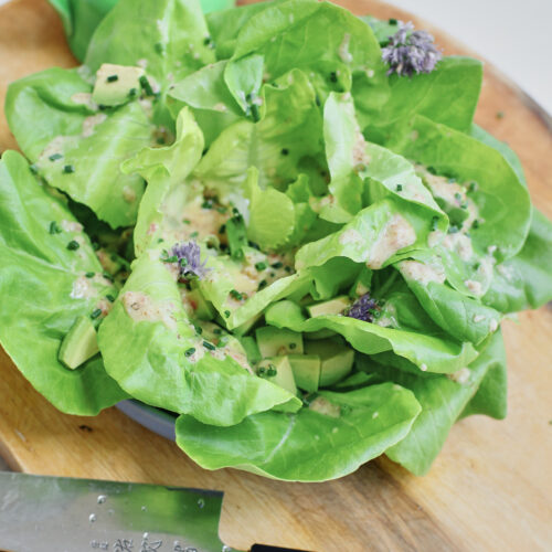 butter lettuce toped with chives, dressing, and cubed avocado