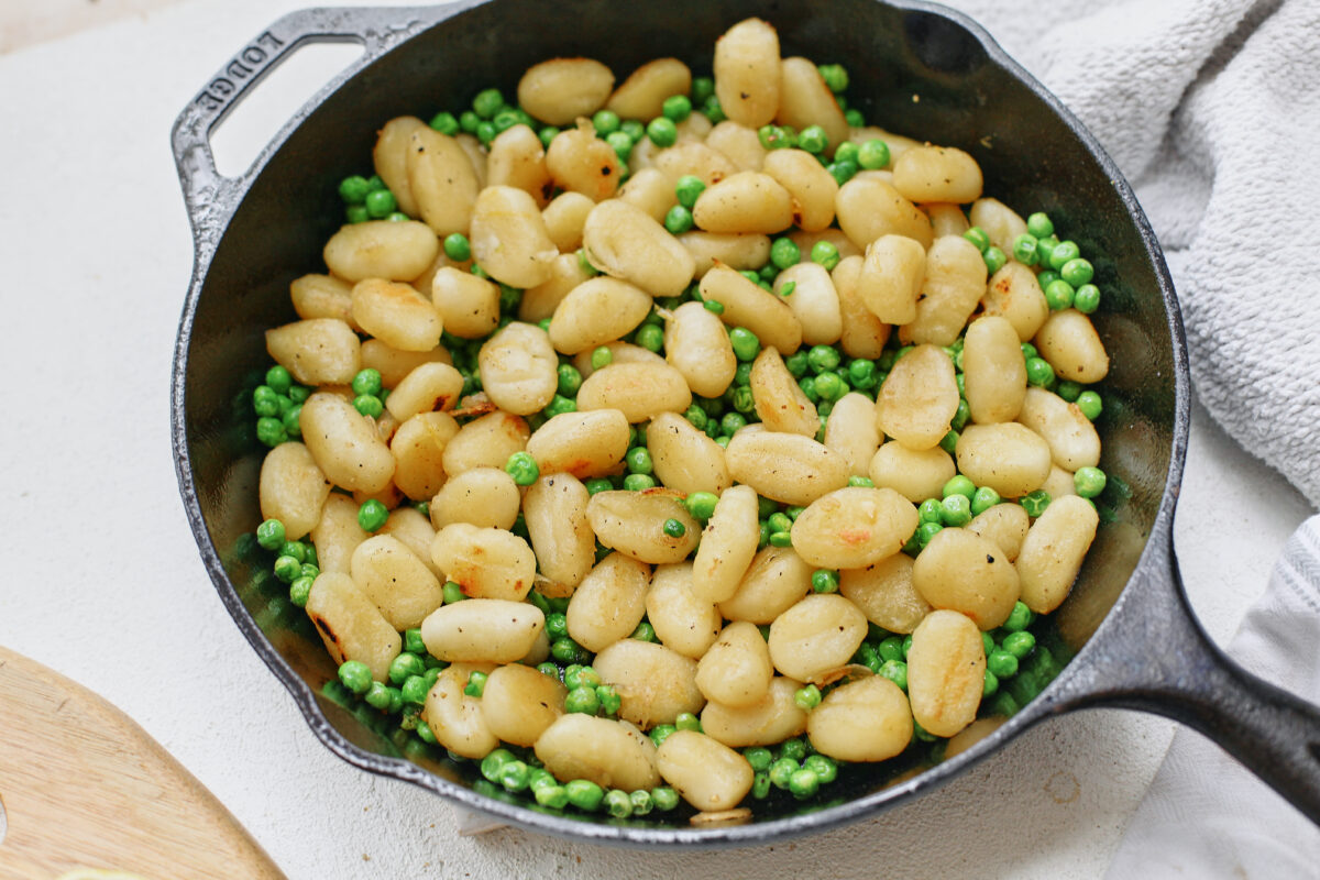 gnocchi after being crisped in a cast iron skillet with green peas mixed in
