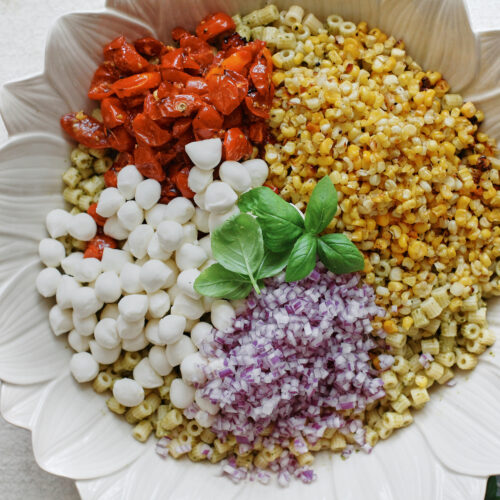 Ditalini pasta topped with roasted corn, tomatoes, mozzarella pearls, red onion and fresh basil