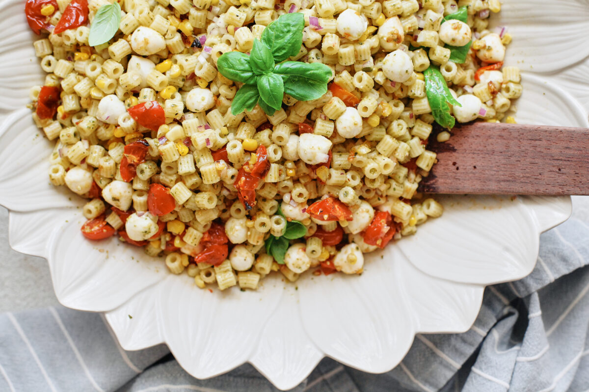 Roasted corn pesto pasta salad with tomatoes, mozzarella pearls, red onion and fresh basil