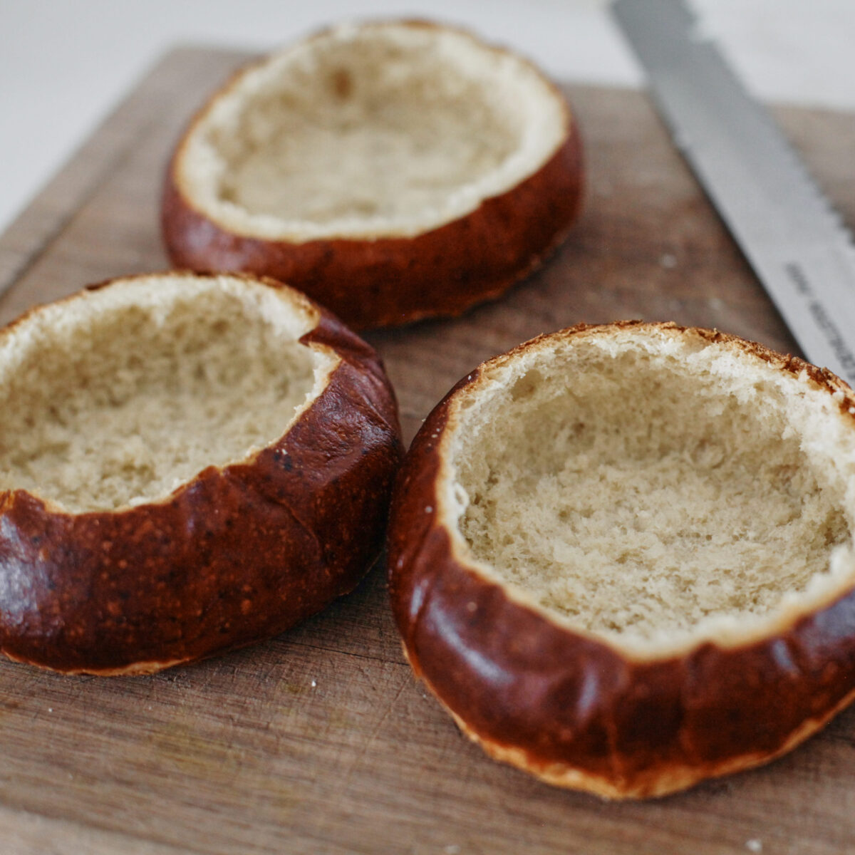 three pretzel buns with the middle scooped out to make a bowl