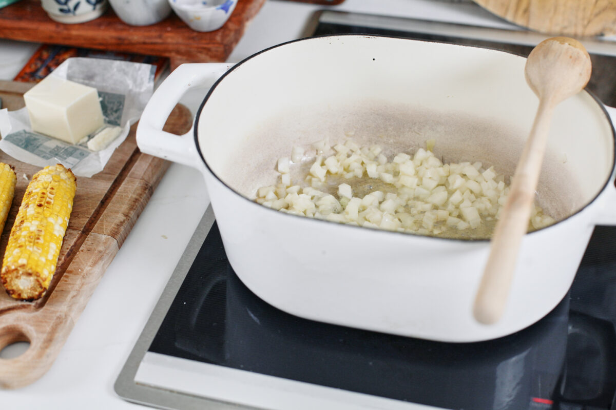 diced onion sautéing in a white dutch oven on the stove