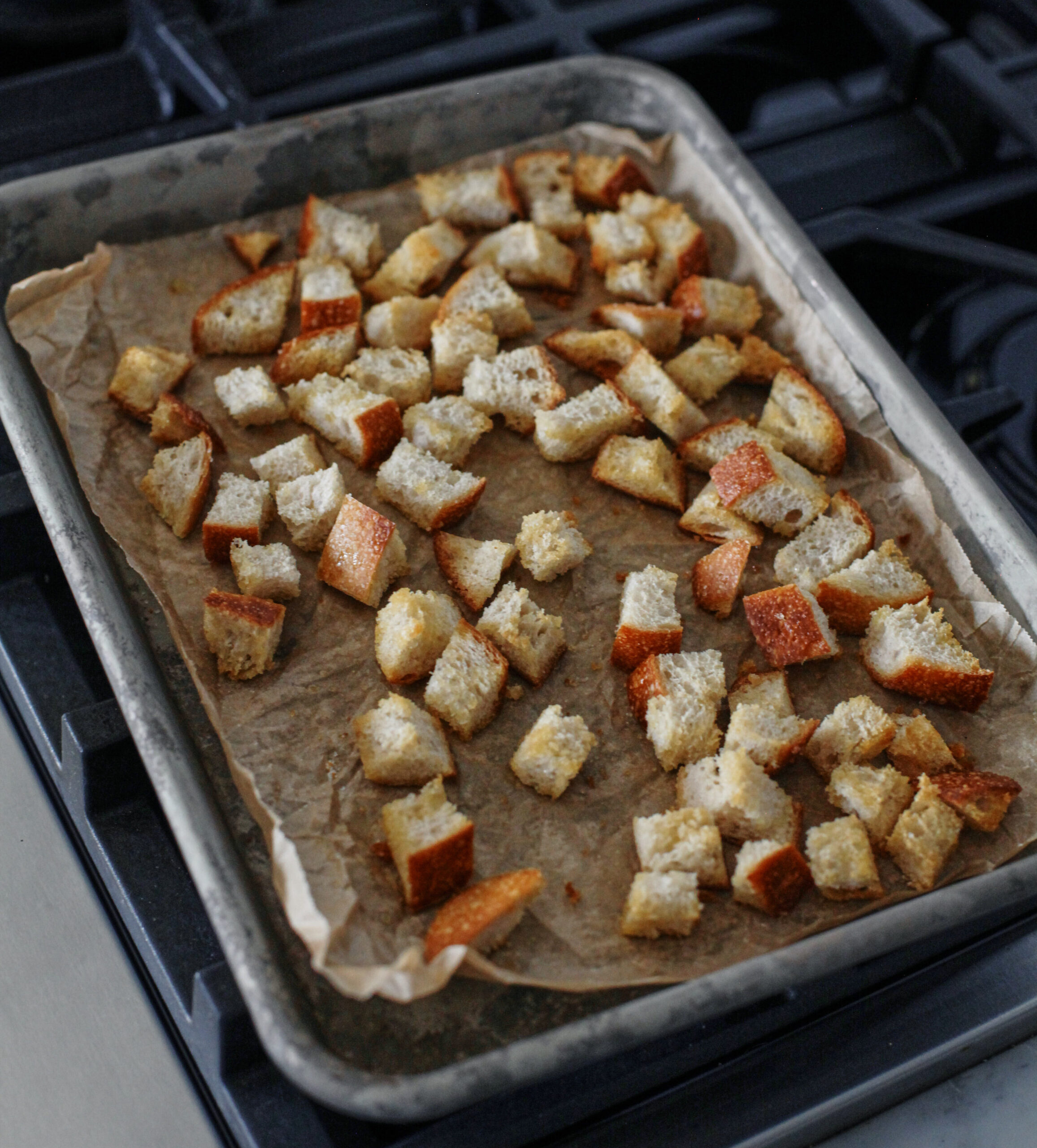 croutons toasting on a parchment-lined sheet pan