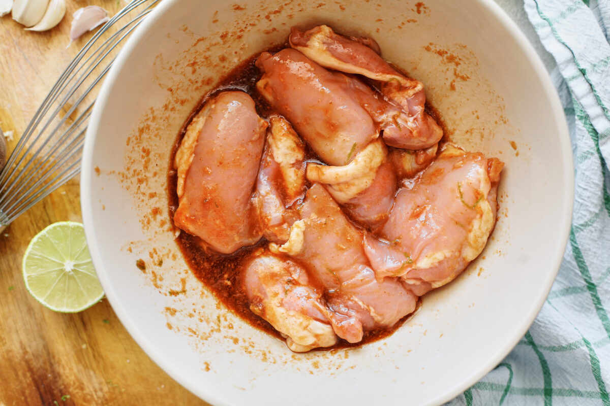 chicken thighs marinating in a large white bowl