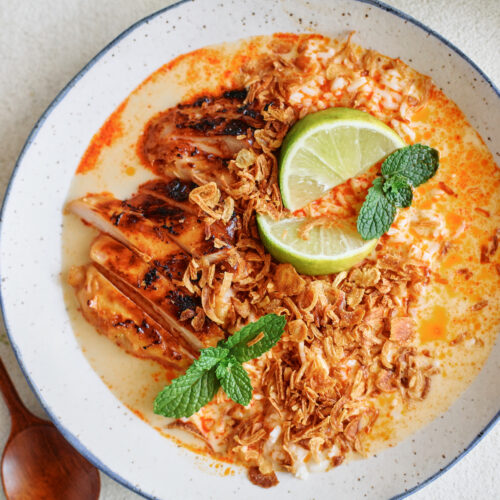 spicy yellow curry chicken & brothy rice bowl topped with crispy shallots, mint, and lime wedges