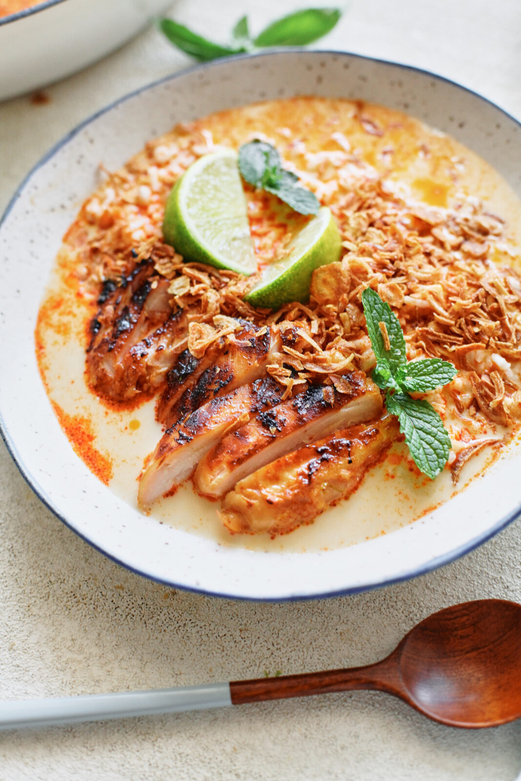 spicy yellow curry chicken & brothy rice bowl topped with crispy shallots, mint, and lime wedges