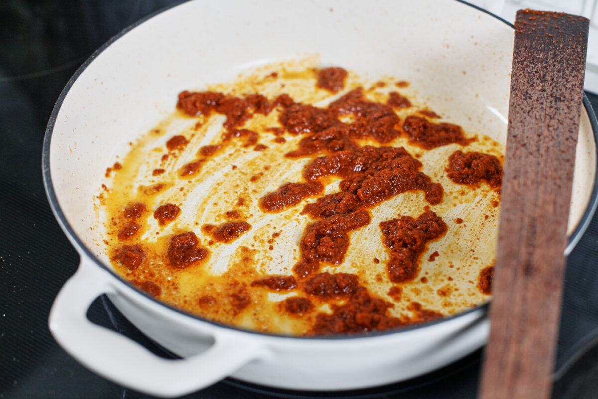 curry paste being sautéed in a large white skillet